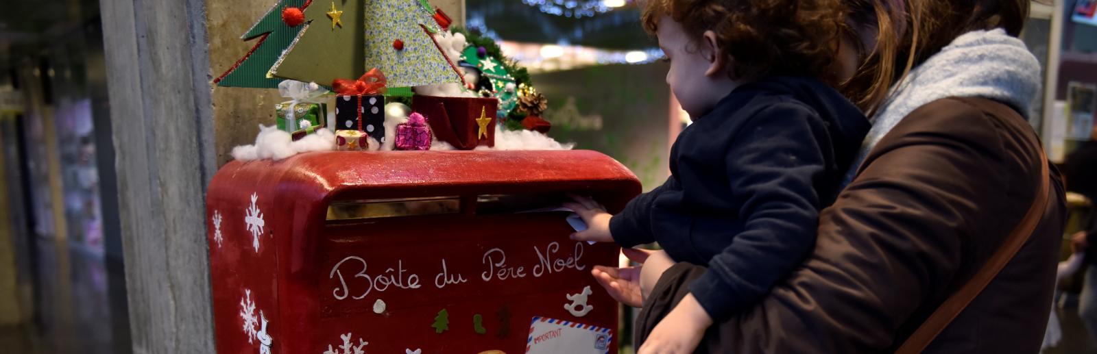 Atelier de noël à l’hôpital Necker, un enfant et sa mère déposant une lettre dans la boite aux lettres décorés