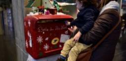 Atelier de noël à l’hôpital Necker, un enfant et sa mère déposant une lettre dans la boite aux lettres décorés